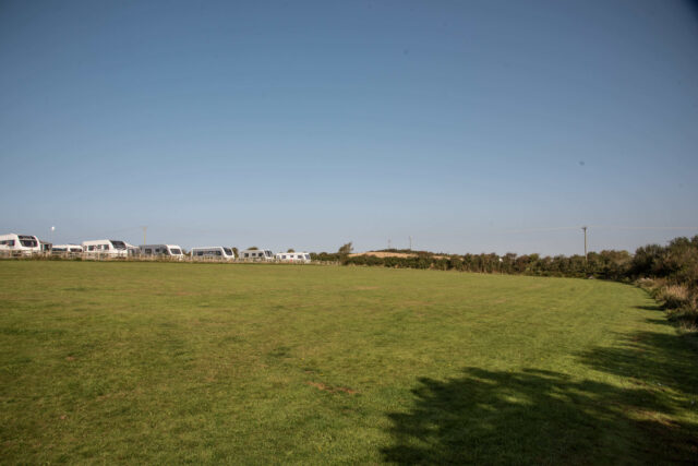 A mown fields with caravans in the background